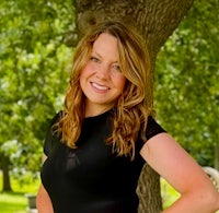 a woman in a black dress posing in front of a tree